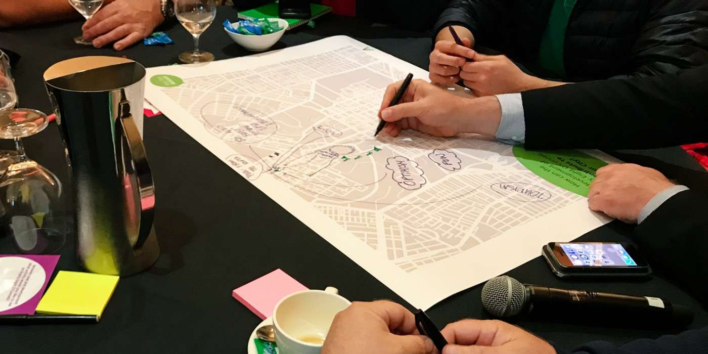 overhead view of table with town planning drawing with hands holding pens